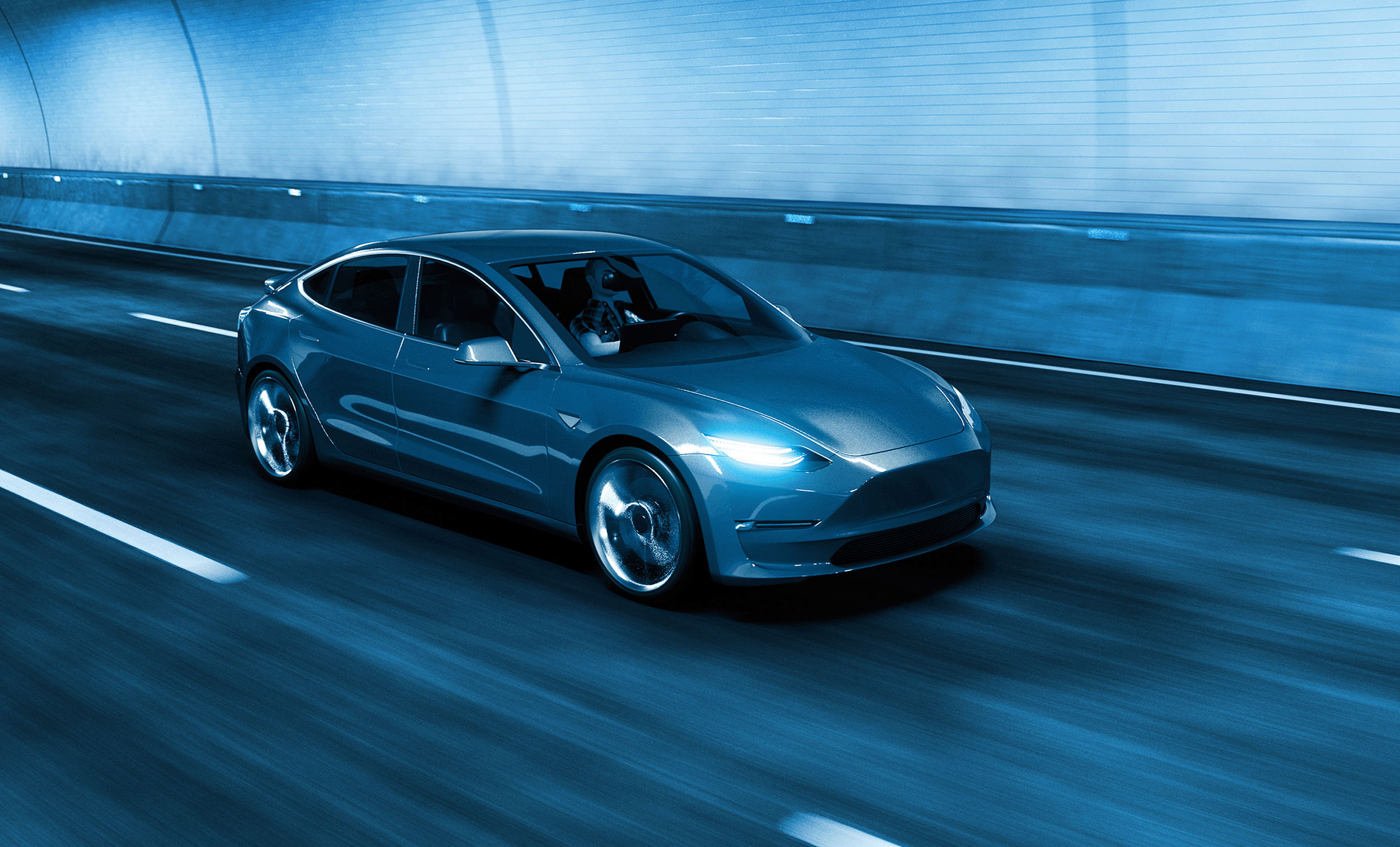 A silver car driving through a well-lit tunnel, highlighting the importance of automotive insurance and road safety in various driving conditions.
