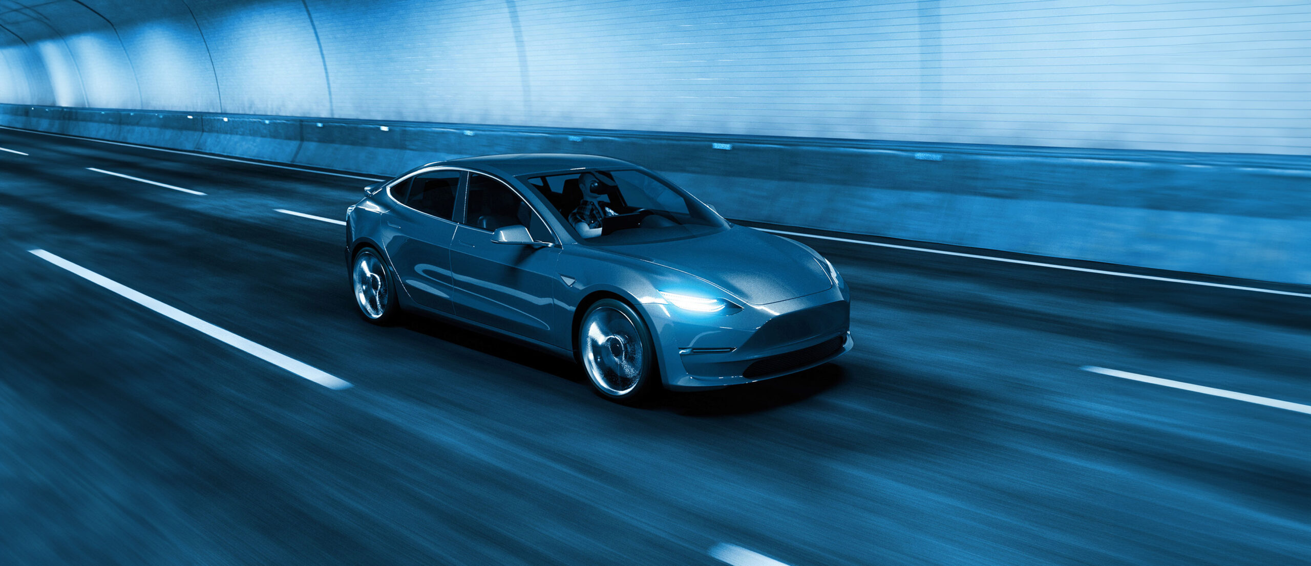 A silver car driving through a well-lit tunnel, highlighting the importance of automotive insurance and road safety in various driving conditions.